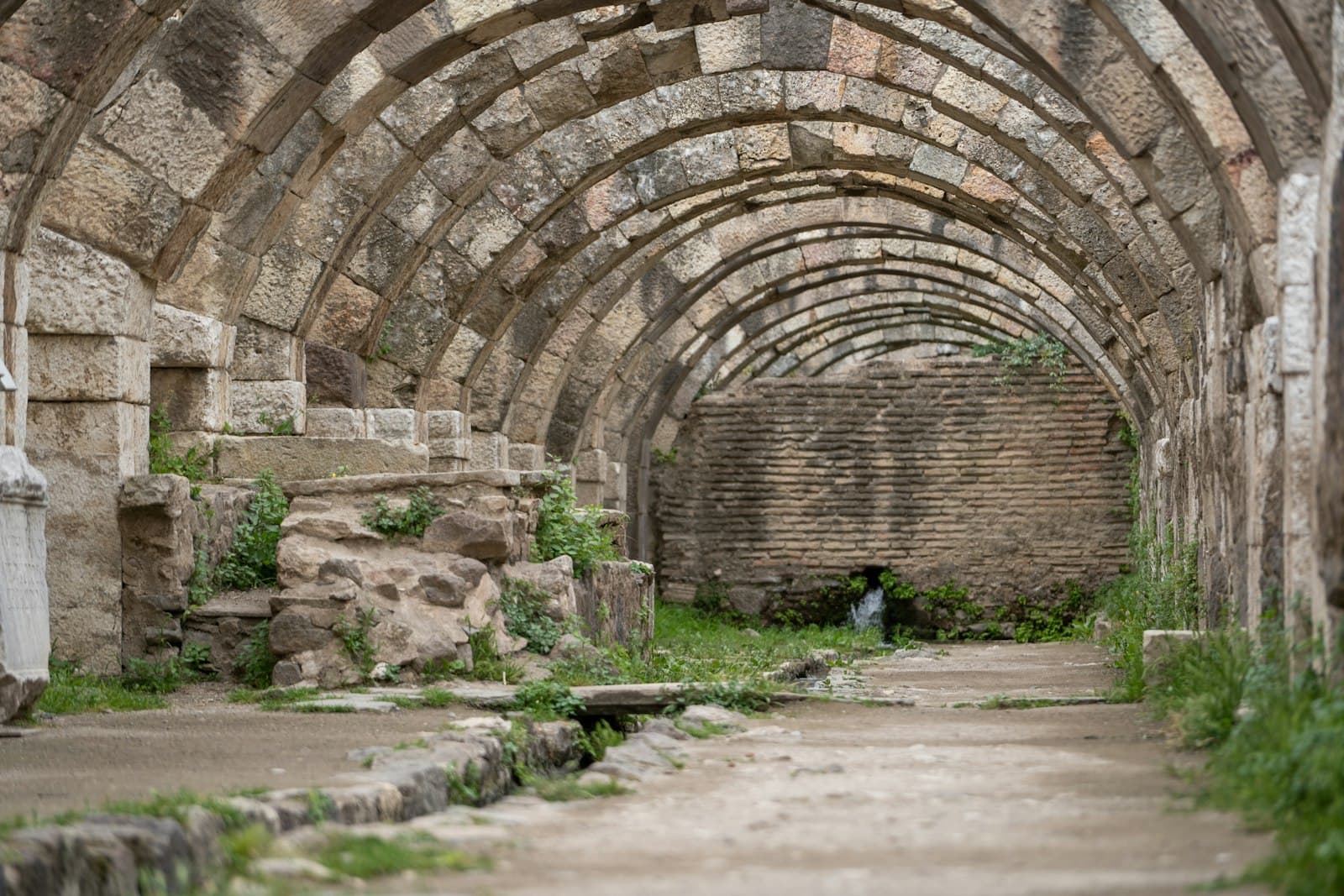 A vaulted stone arcade receding into shadow — temple glory and ruin
