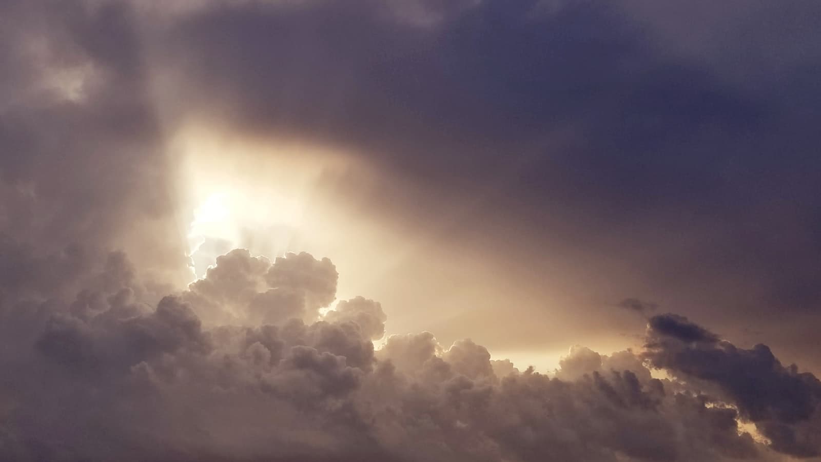 Warm light breaking through heavy cloud — the day of the Lord